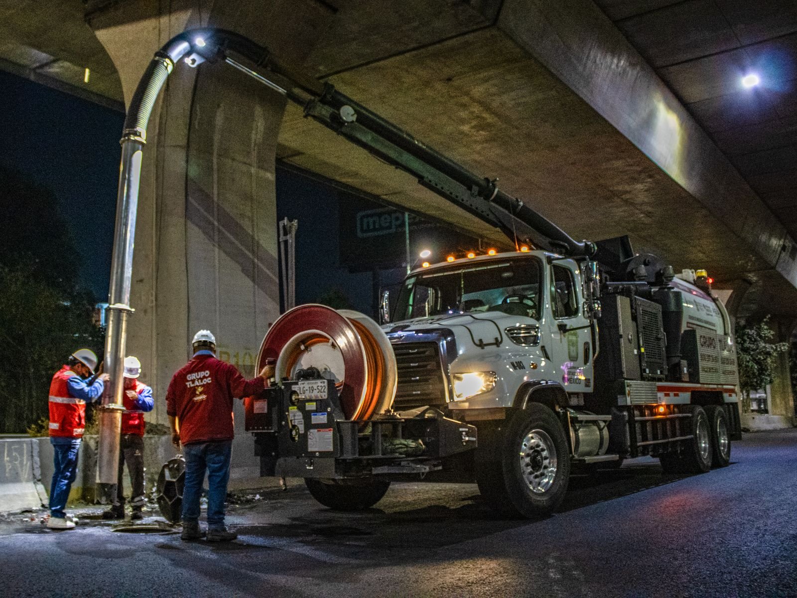 Workers operating a vacuum truck at night