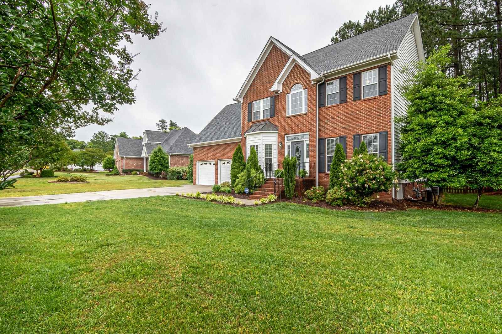 A two-story brick home with a manicured lawn